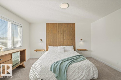 Bedroom featuring a full-height wood accent wall, neutral carpeting, and a large window with horizontal blinds - 21003 131 Avenue, Edmonton, AB 