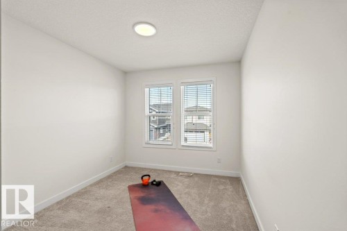 Bright interior room featuring neutral wall paint, light-colored carpet flooring, and white baseboards - 21003 131 Avenue, Edmonton, AB 