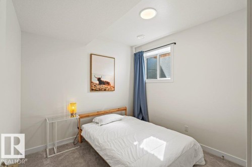 Carpeted room featuring a single window with blinds and blue drapes, white walls, and flush-mount ceiling lighting - 21003 131 Avenue, Edmonton, AB 