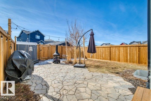 Fenced backyard featuring a large flagstone patio, a garden shed, a wood fence perimeter, and string lighting - 21003 131 Avenue, Edmonton, AB 