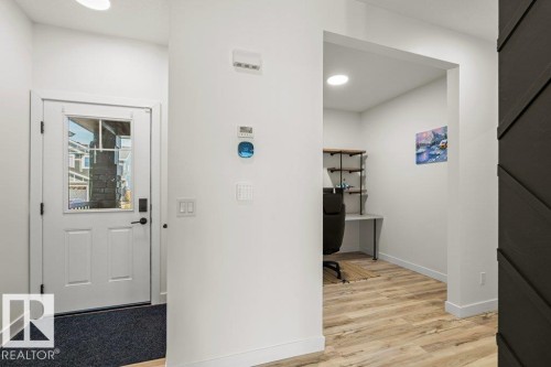 Entryway featuring a white door with a window and black hardware, leading to an interior space with wood-finish flooring - 21003 131 Avenue, Edmonton, AB 