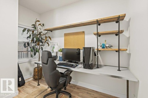 Integrated desk system with built-in shelving, wood-finish flooring, and a window with blinds - 21003 131 Avenue, Edmonton, AB 