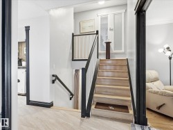 Staircase featuring wood steps, white risers, and a black handrail with white balusters - 