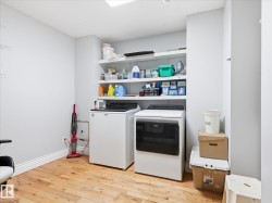 Dedicated laundry area featuring wood-finish flooring and multiple wall-mounted shelves - 