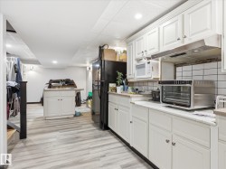 Kitchenette featuring white cabinetry, a white subway tile backsplash, and light-tone wood-finish flooring - 