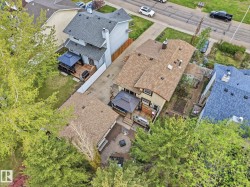 Aerial view of a residential property featuring a light-colored exterior, an attached deck with a dark gazebo, and a paved driveway - 