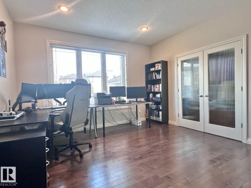 Spacious room featuring rich wood-finish flooring and a wide window providing natural light - 820 Drysdale Run, Edmonton, AB - Indoor Photo Showing Office