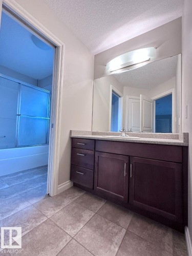 Bathroom vanity featuring a light-toned countertop, integrated sink, and dark wood-finish cabinetry - 820 Drysdale Run, Edmonton, AB - Indoor