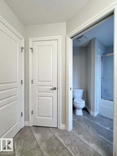 Interior hallway with textured ceiling and two paneled doors, one featuring a polished chrome lever handle - 820 Drysdale Run, Edmonton, AB - Indoor