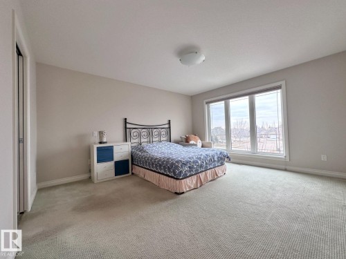 Spacious room featuring neutral wall tones, plush carpeting, a large multi-pane window, and a built-in closet with bifold doors - 820 Drysdale Run, Edmonton, AB - Indoor Photo Showing Bedroom