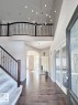 Two-story entryway with a decorative modern chandelier, hardwood-finish flooring, and a carpeted staircase with a dark wood and wrought iron railing - 820 Drysdale Run, Edmonton, AB  - Indoor Photo Showing Other Room 