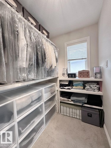 Walk-in closet featuring built-in shelving, hanging rods, and a window with blinds - 820 Drysdale Run, Edmonton, AB - Indoor With Storage