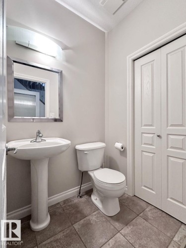 Pedestal sink with chrome faucet, complemented by a rectangular framed mirror and modern wall-mounted lighting - 820 Drysdale Run, Edmonton, AB - Indoor Photo Showing Bathroom