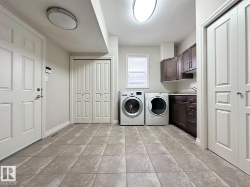 Dedicated laundry room featuring large format tile flooring and a built-in sink - 820 Drysdale Run, Edmonton, AB - Indoor Photo Showing Laundry Room