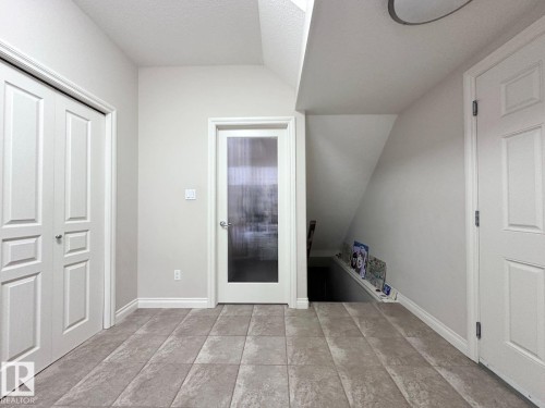Entryway featuring large format tile flooring, a frosted glass door, and white panel doors - 820 Drysdale Run, Edmonton, AB - Indoor Photo Showing Other Room