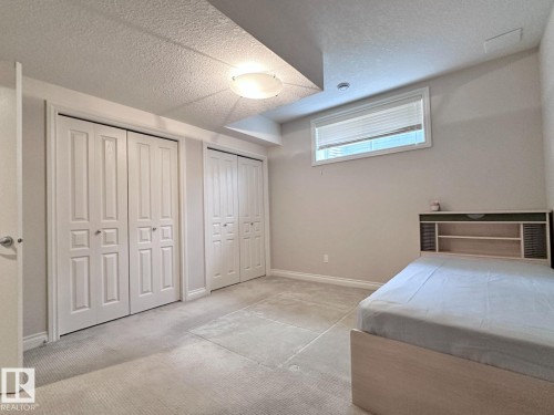 Neutral-toned carpeting extends throughout this room, featuring two sets of bi-fold closet doors with panel detailing - 820 Drysdale Run, Edmonton, AB - Indoor