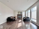 Spacious interior featuring wood-finish flooring, a traditional fireplace with a dark wood mantel, multiple windows with cellular blinds, recessed ceiling lighting, and neutral wall tones - 820 Drysdale Run, Edmonton, AB  - Indoor Photo Showing Living Room With Fireplace 