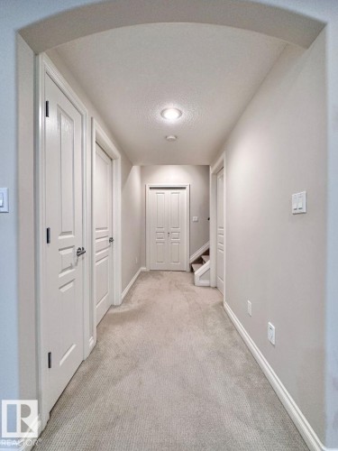 Archway entry to a carpeted hallway featuring neutral wall tones, white trim, and recessed lighting - 820 Drysdale Run, Edmonton, AB - Indoor Photo Showing Other Room