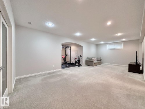 Spacious lower-level room featuring light gray carpet, recessed lighting, and an arched entryway - 820 Drysdale Run, Edmonton, AB - Indoor Photo Showing Basement