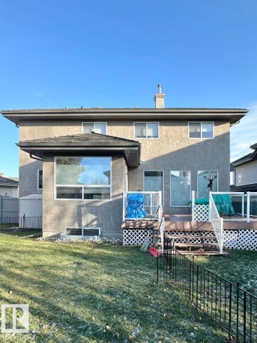 Stucco exterior featuring multiple windows and a rear deck with white railings and lattice skirting - 820 Drysdale Run, Edmonton, AB - Outdoor With Deck Patio Veranda