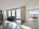 Open-concept living space featuring rich wood-finish flooring, a fireplace with a wood mantle, numerous windows with blinds, and recessed lighting - 820 Drysdale Run, Edmonton, AB  - Indoor Photo Showing Living Room With Fireplace 