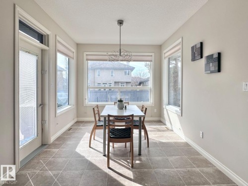 Room featuring large windows, a glass-paneled door, tile flooring, a contemporary ceiling light fixture, and light-toned wall finishes - 820 Drysdale Run, Edmonton, AB - Indoor Photo Showing Dining Room