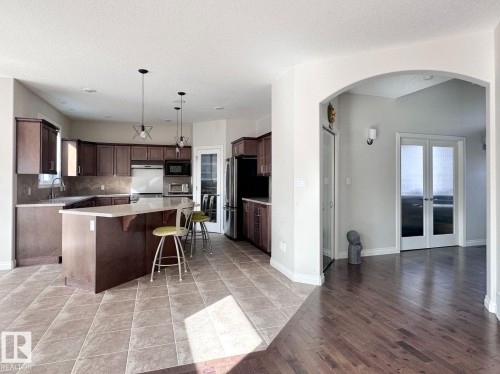 Kitchen featuring dark wood-finish cabinetry, light-toned countertops, and a central island with pendant lighting - 820 Drysdale Run, Edmonton, AB - Indoor Photo Showing Kitchen