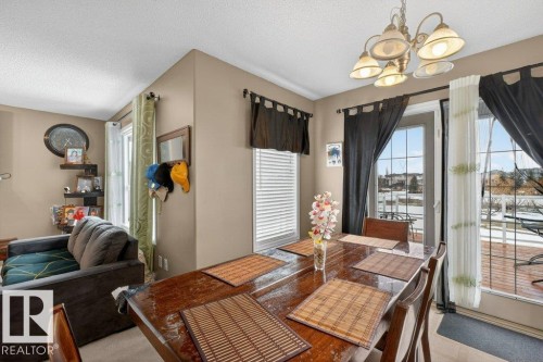 Dining area with a polished wooden table, an overhead chandelier, and direct access to an outdoor patio through glass doors - 16107 92 Street, Edmonton, AB - Indoor