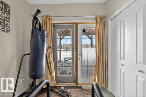 This room features light-colored walls and a double-door entry with glass panels, providing views of an exterior structure and the sky - 16107 92 Street, Edmonton, AB - Indoor Photo Showing Other Room