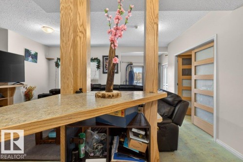 Open concept living area with light wood accents and a modern sliding door with frosted glass panels - 16107 92 Street, Edmonton, AB - Indoor
