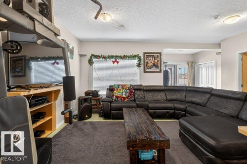 The property features a spacious living area with carpeted floors, a large window with horizontal blinds, and a door leading outdoors - 16107 92 Street, Edmonton, AB - Indoor Photo Showing Living Room