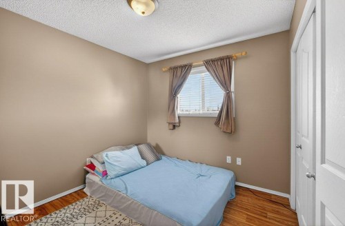 This room features a window with blinds, hardwood flooring, and a white paneled door - 16107 92 Street, Edmonton, AB - Indoor Photo Showing Bedroom