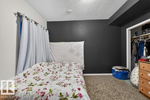 This room features a neutral-toned carpet, a dark accent wall, and a closet with an open doorway - 16107 92 Street, Edmonton, AB - Indoor Photo Showing Bedroom
