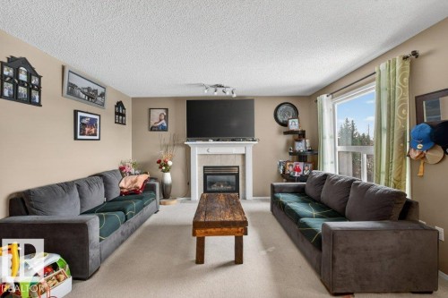 Living room featuring light-colored walls, carpeted floors, and a fireplace with a white mantel - 16107 92 Street, Edmonton, AB - Indoor Photo Showing Living Room With Fireplace