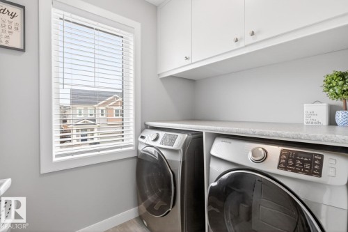 Upstairs Laundry Room featuring Countertop, Storage, and Samsung Front Load Washer/Dryer. - 20023 17A Avenue, Edmonton, AB - Indoor Photo Showing Laundry Room