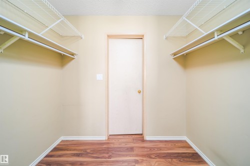 Walk-in closet featuring wood-finish flooring, light-toned walls, and wire shelving with integrated hanging rods - 213 5065 31 Avenue, Edmonton, AB - Indoor Photo Showing Other Room