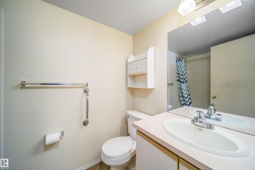 Bathroom featuring a single vanity with an integrated sink, polished chrome faucet, and a large wall-mounted mirror - 213 5065 31 Avenue, Edmonton, AB - Indoor Photo Showing Bathroom