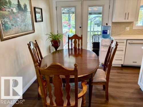 Dining area featuring wood-finish flooring, light-toned walls, and double glass-paneled doors - 4805 53Ave, Willingdon, AB - Indoor Photo Showing Dining Room