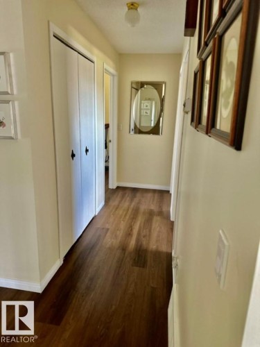 Hallway featuring wood-finish flooring, light-toned walls, white trim, and a ceiling-mounted light fixture - 4805 53Ave, Willingdon, AB - Indoor Photo Showing Other Room