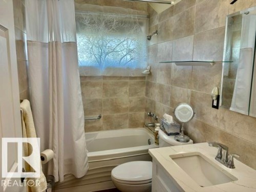 Bathroom with floor-to-ceiling ceramic tile, a single vanity with stone-finish countertop, undermount sink, and chrome fixtures - 4805 53Ave, Willingdon, AB - Indoor Photo Showing Bathroom