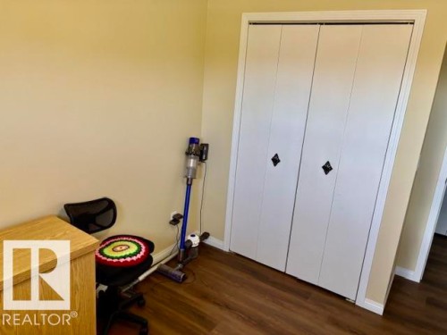 Wide bi-fold closet doors with decorative black hardware, framed by white trim - 4805 53Ave, Willingdon, AB - Indoor