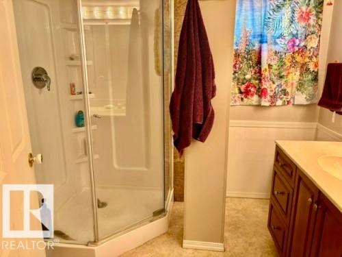 Corner shower enclosure with clear glass panels, a single chrome fixture, and integrated shelving - 4805 53Ave, Willingdon, AB - Indoor Photo Showing Bathroom