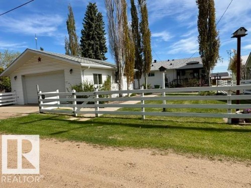 White-paneled exterior with a prominent attached garage and a white picket fence - 4805 53Ave, Willingdon, AB - Outdoor