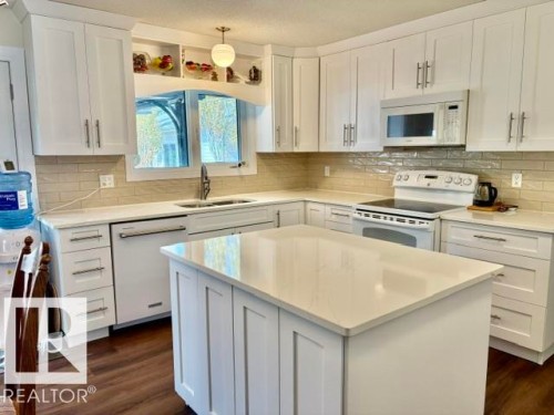 Contemporary kitchen featuring white shaker cabinetry, light-toned countertops, and a subway tile backsplash - 4805 53Ave, Willingdon, AB - Indoor Photo Showing Kitchen With Double Sink