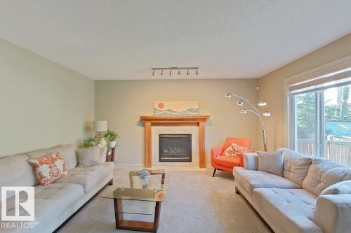 Living area featuring a fireplace with a wood-finish mantel and tile surround, complemented by track lighting and a sliding glass door - 1206 Mckinney Court, Edmonton, AB - Indoor Photo Showing Living Room With Fireplace