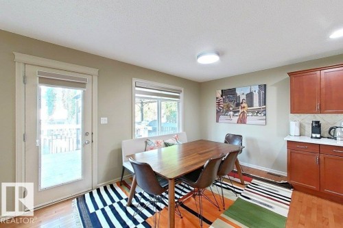 Dining area featuring wood-finish flooring and a full-light patio door leading to an outdoor deck - 1206 Mckinney Court, Edmonton, AB - Indoor Photo Showing Dining Room