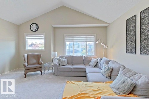 Living area featuring a vaulted ceiling, light-colored carpeting, multiple windows with blinds, and neutral-toned walls - 1206 Mckinney Court, Edmonton, AB - Indoor Photo Showing Living Room