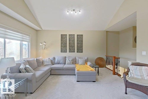 Spacious room featuring vaulted ceilings, a large window, light-toned walls, track lighting, and carpet flooring - 1206 Mckinney Court, Edmonton, AB - Indoor Photo Showing Living Room