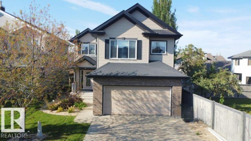 Two-story residence featuring light-toned siding, dark roofline, and attached garage with a light-colored garage door - 1206 Mckinney Court, Edmonton, AB - Outdoor