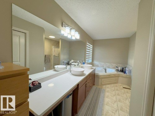 Dual vessel sinks set on a white countertop with a full-width wall mirror - 1206 Mckinney Court, Edmonton, AB - Indoor Photo Showing Bathroom